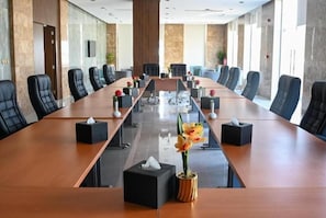 A conference room with a long table, black chairs, and a potted plant. - Corp Yanbu Hotel B2 (Yanbu)