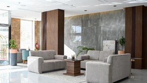 A modern lobby with a marble reception desk, two sofas, a coffee table, and a fire extinguisher. - Corp Yanbu Hotel B2 (Yanbu)