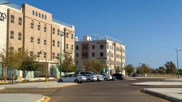 A multi-story hotel with a modern architectural design, featuring a parking lot with several cars.
