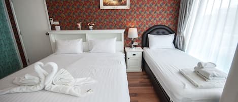 A hotel room with two beds, a painting on the wall, and a window with curtains.