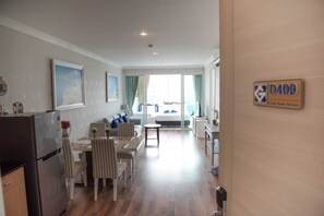 A hotel room with a dining area, a bed with a view, and a sign indicating room service availability. - D409 Spacious 3-bedroom apartment in serene Huahin with Playground near Beach (Huahin)