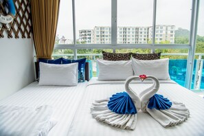 Een hotelkamer met een bed, kussens en een decoratieve zwaan van handdoeken.