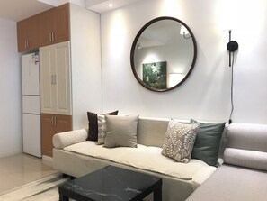 A modern living room with a sofa, a coffee table, and a large mirror.