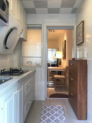 A compact kitchen with white cabinetry, a built-in microwave, and a gas stove. - Innocondo Extended Stay West Yan'an Road (Shanghai)
