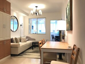 A modern living room with a sofa, dining table, chairs, a chandelier, and large windows. - Innocondo Extended Stay West Yan'an Road (Shanghai)