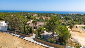 A coastal property with a paved driveway, a stone wall, and a view of the sea. - Quinta dos Loendros |  9 bedrooms | Carvoeiro | Jacuzzi (Lagoa)