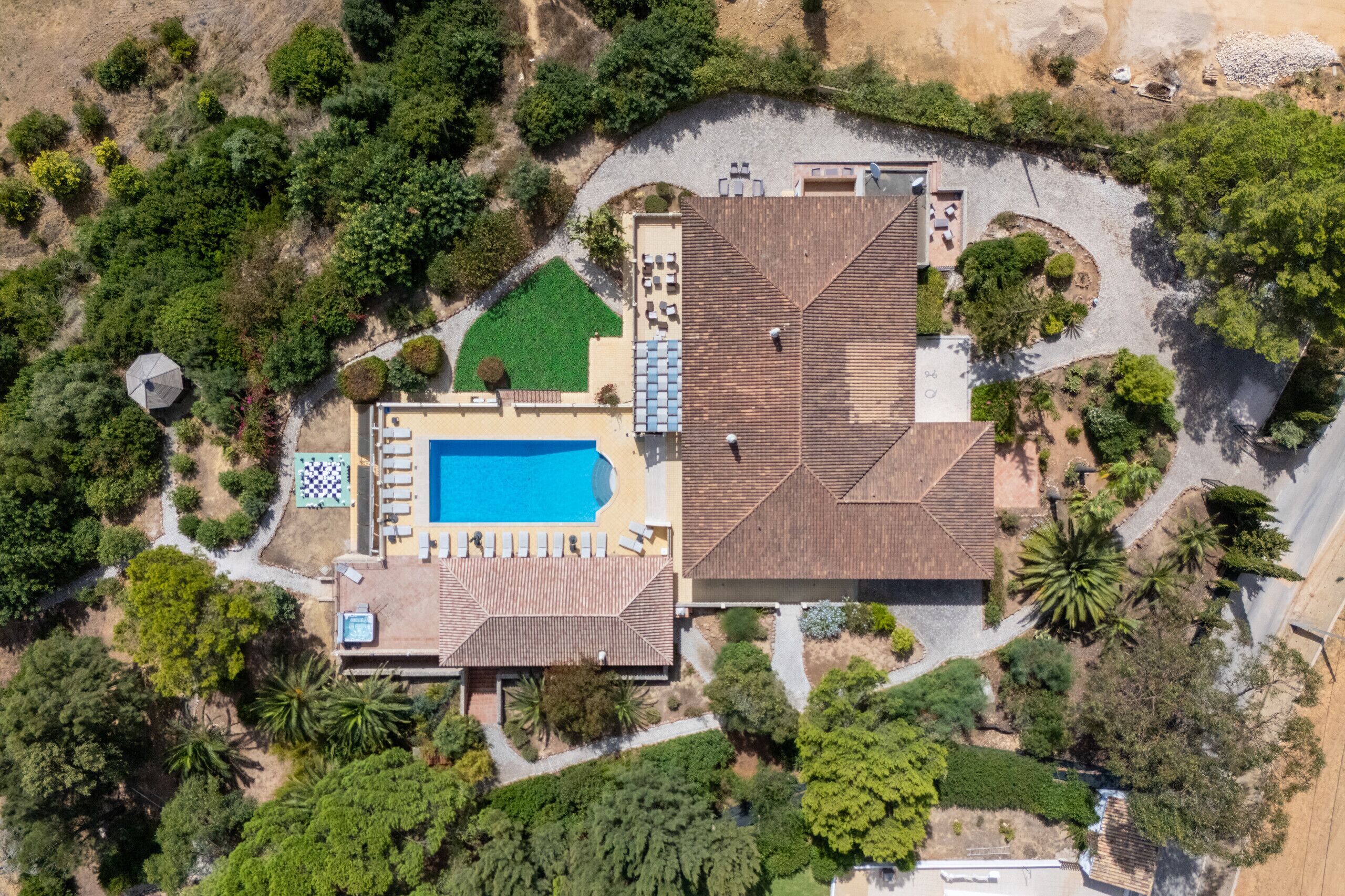Propiedad residencial con piscina, mobiliario de exterior y jardín ajardinado.