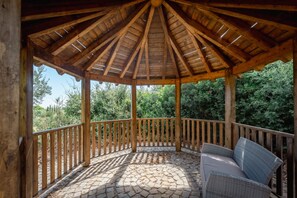 Un gazebo in legno con pavimento piastrellato e una panchina.