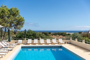 A poolside area with lounge chairs and a view of the sea. - Quinta dos Loendros |  9 bedrooms | Carvoeiro | Jacuzzi (Lagoa)