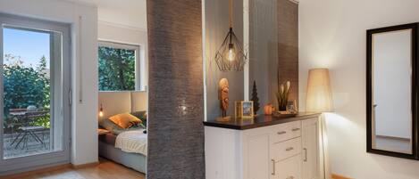 A modern interior with a dining area, a sofa, a cabinet, and a large window.