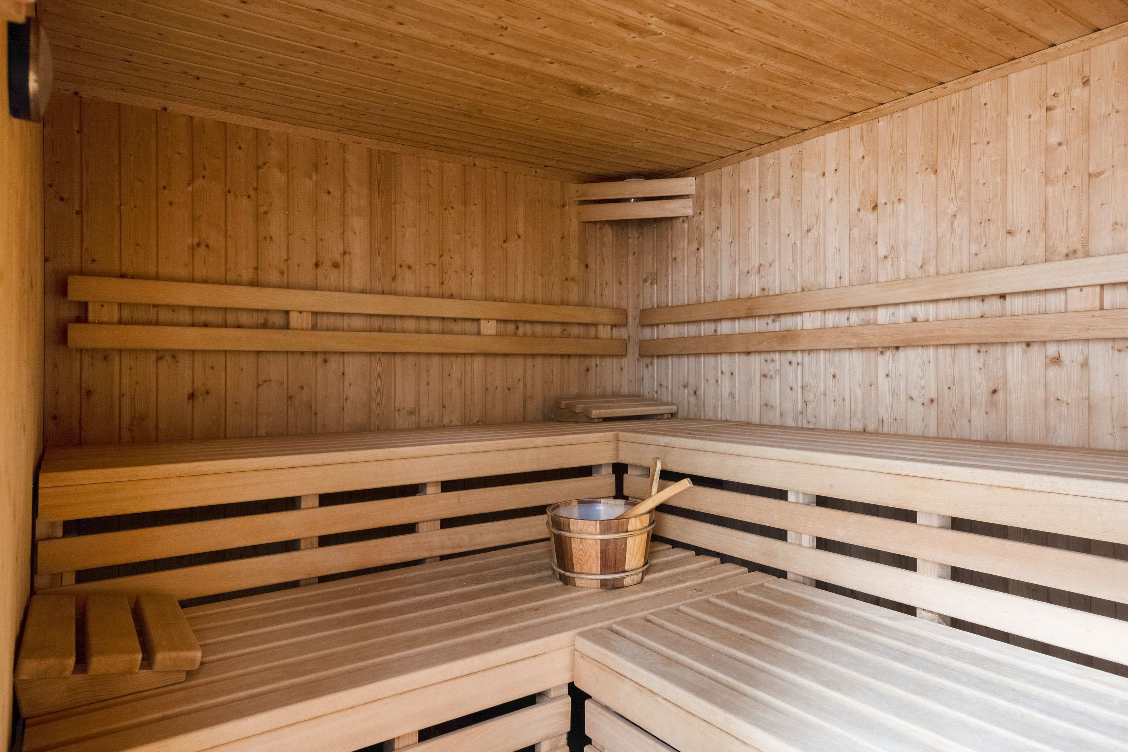 Una sauna con bancos de madera y un balde de madera.