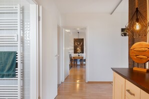 Un intérieur moderne avec un plancher en bois, un coin repas comprenant une table et des chaises, et un espace cuisine doté d’un comptoir et d’un luminaire suspendu.