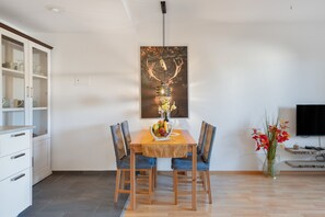 Un coin repas avec une table en bois, deux chaises, un vase de fleurs et un tableau accroché au mur.