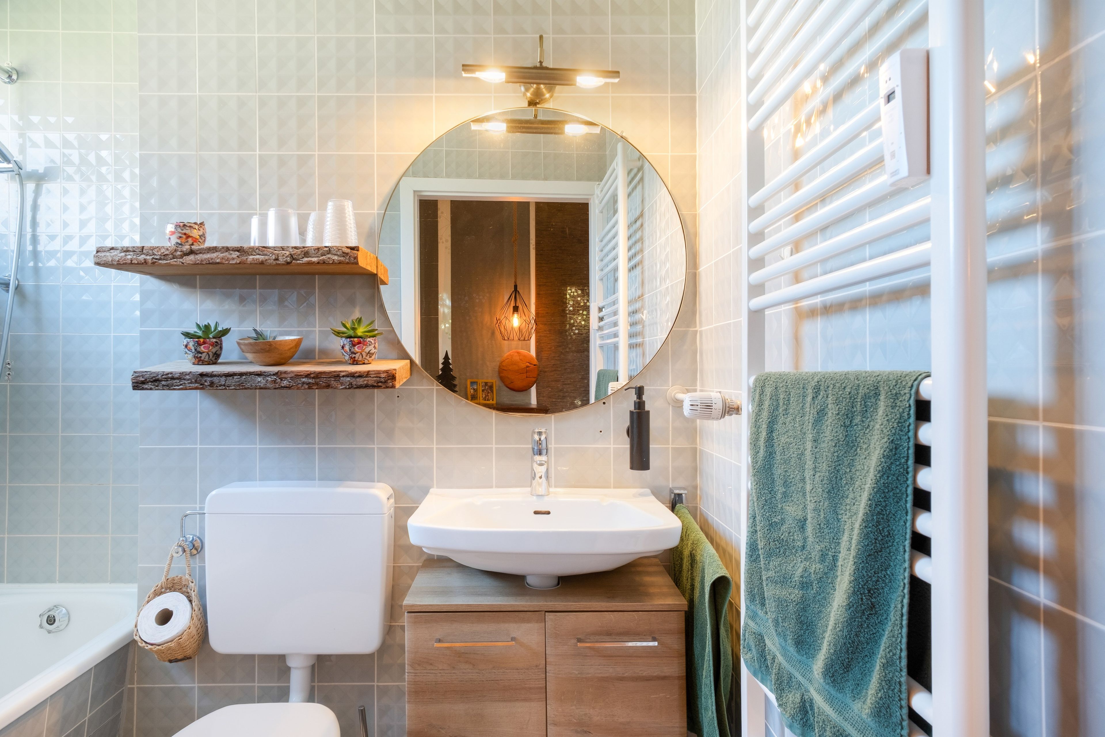 Ein Badezimmer mit Toilette, Waschbecken und Dusche. An der Wand befinden sich Dekorationen und ein Handtuch hängt an der Duschkabinentür.
