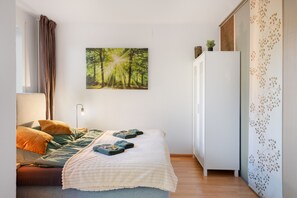 A bedroom with a bed, pillows, a bedside lamp, a wardrobe, and a wall-mounted picture of a forest. - Holiday at 1,000 Meters with Mountain View, Pool, Sauna, and Wi-Fi (Schönwald im Schwarzwald)