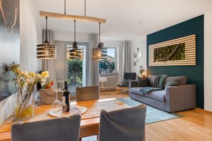 A modern living room with a grey sofa, a dining table with chairs, and pendant lights. - Holiday at 1,000 Meters with Mountain View, Pool, Sauna, and Wi-Fi (Schönwald im Schwarzwald)