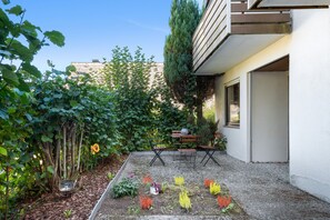 Ein Garten mit verschiedenen Pflanzen und Blumen, einer hölzernen Bank und einem Tisch.