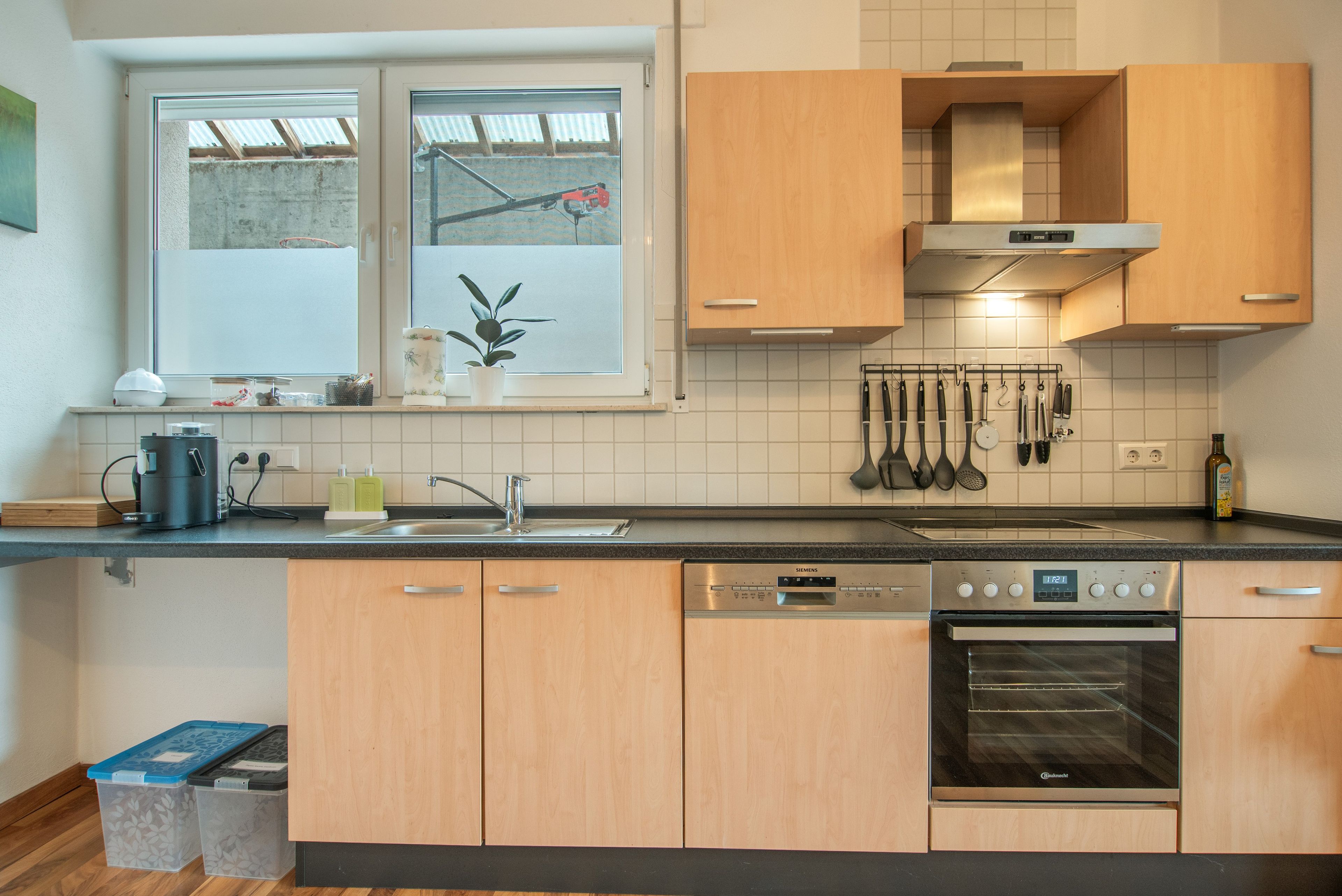 Eine moderne Küche mit Holzausstattung, einem eingebauten Backofen und einem Fenster mit Blick ins Freie.