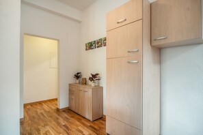 A hallway with wooden flooring, a wooden cabinet with drawers, and a door leading to another room.