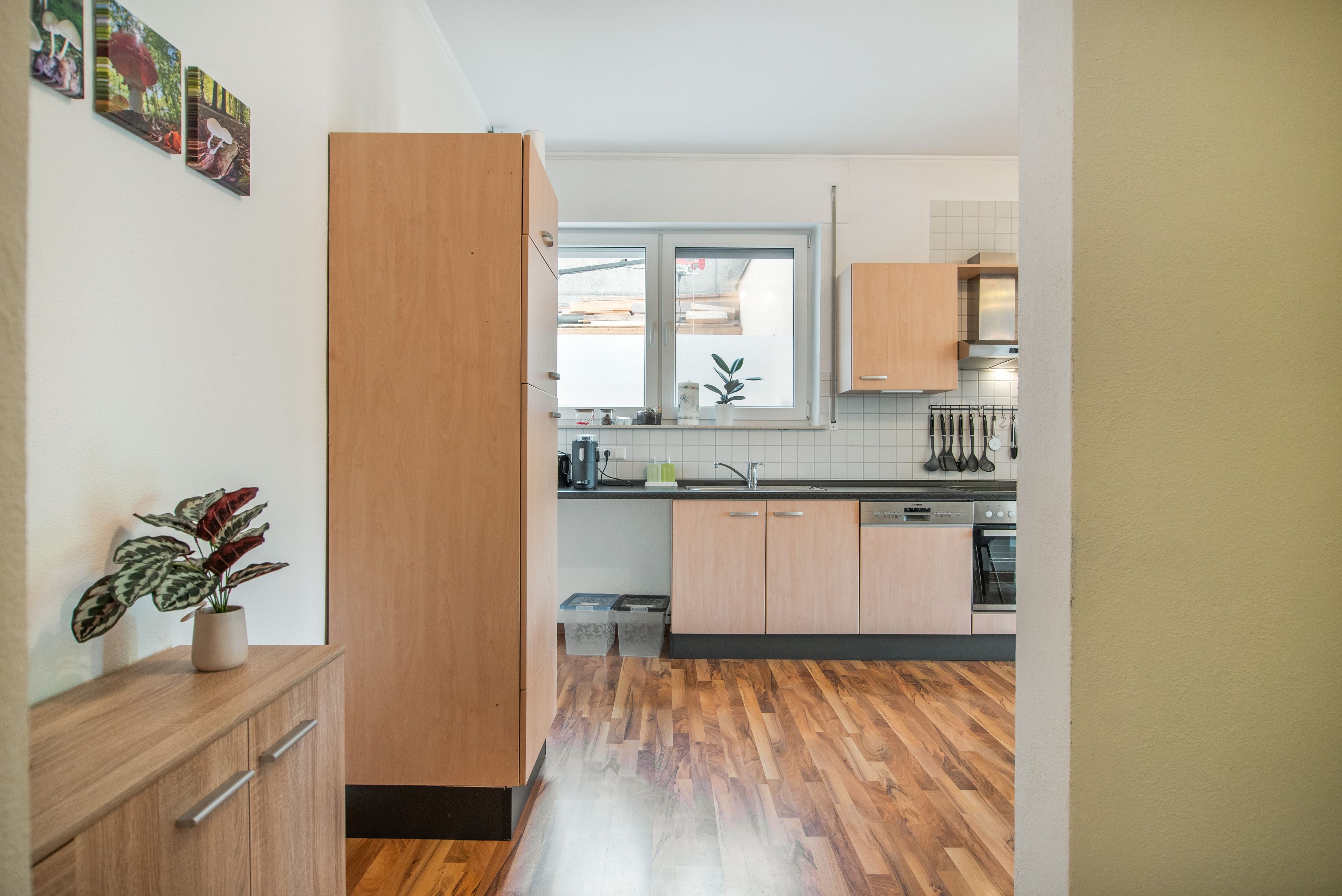 A modern kitchen with wooden cabinets, a built-in oven, and a window with a view of the outside.