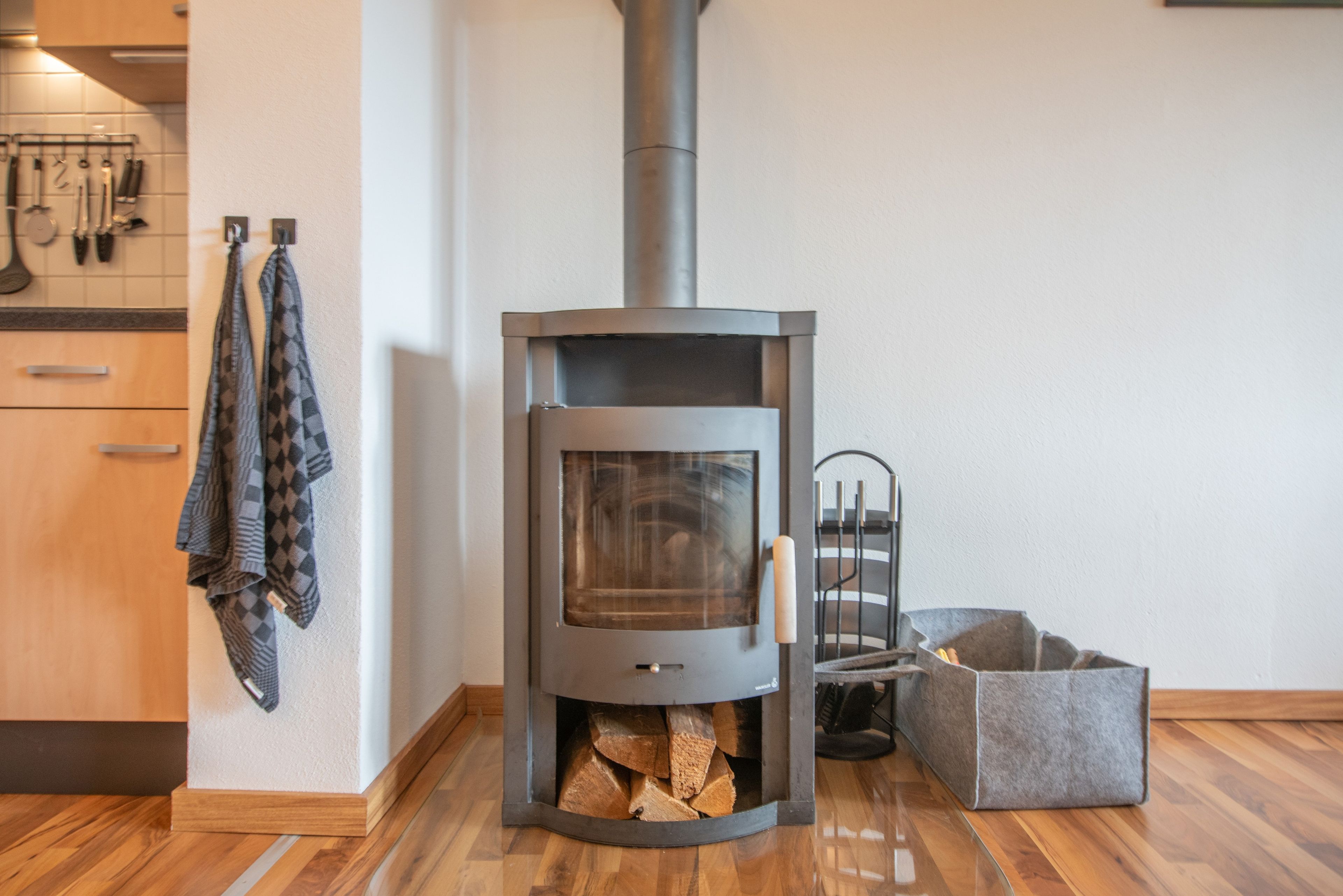 Eine moderne Küche mit Kaminofen, Holzschränken und einem hängenden Handtuchhalter.