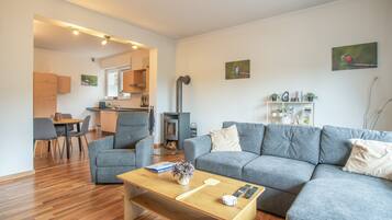 Ein modernes Wohnzimmer mit grauem Sofa, einem Holztisch und einem Essbereich mit Stühlen und Tisch.