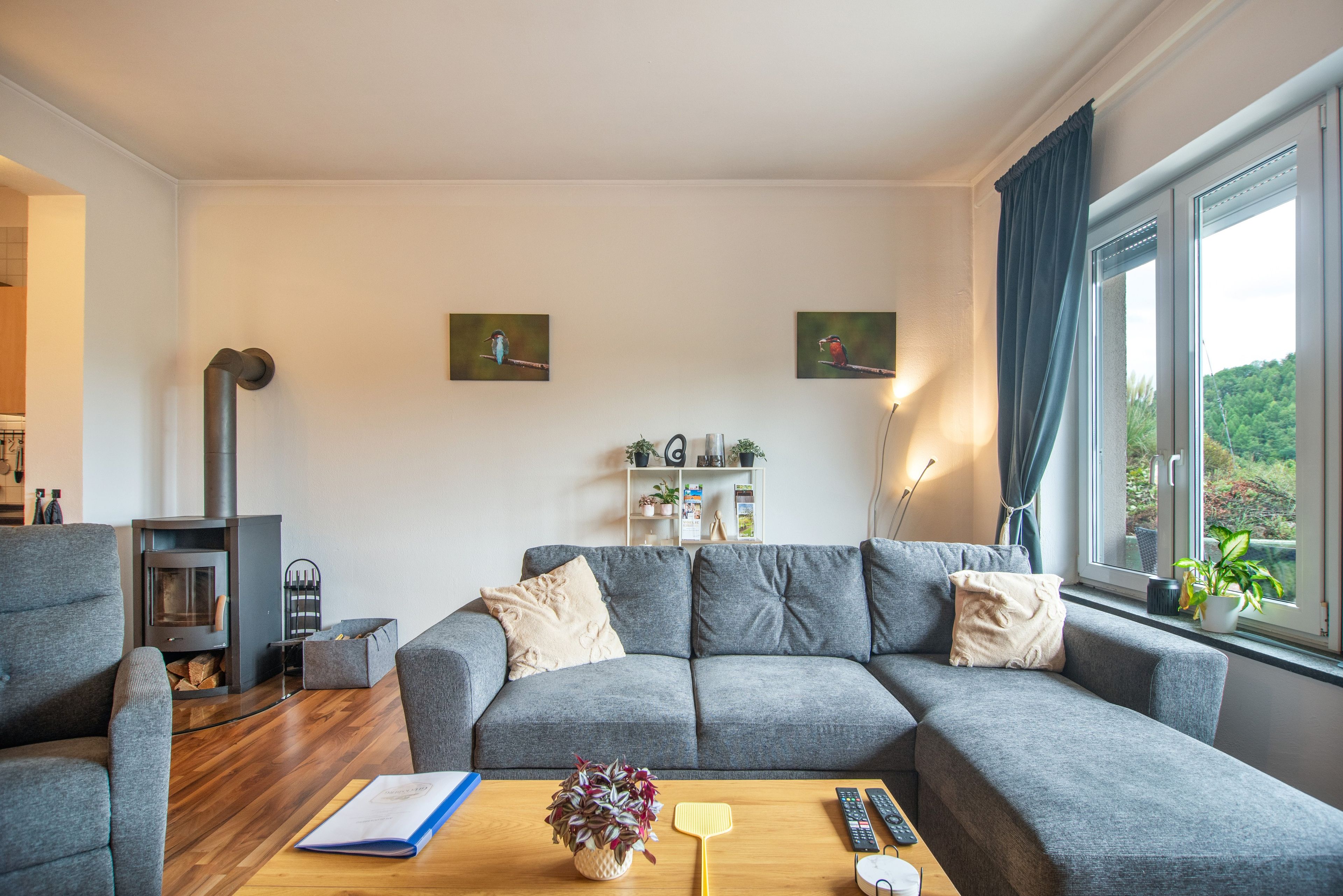 Ein modernes Wohnzimmer mit einem grauen Sofa, einem Holztisch und einem Kamin.