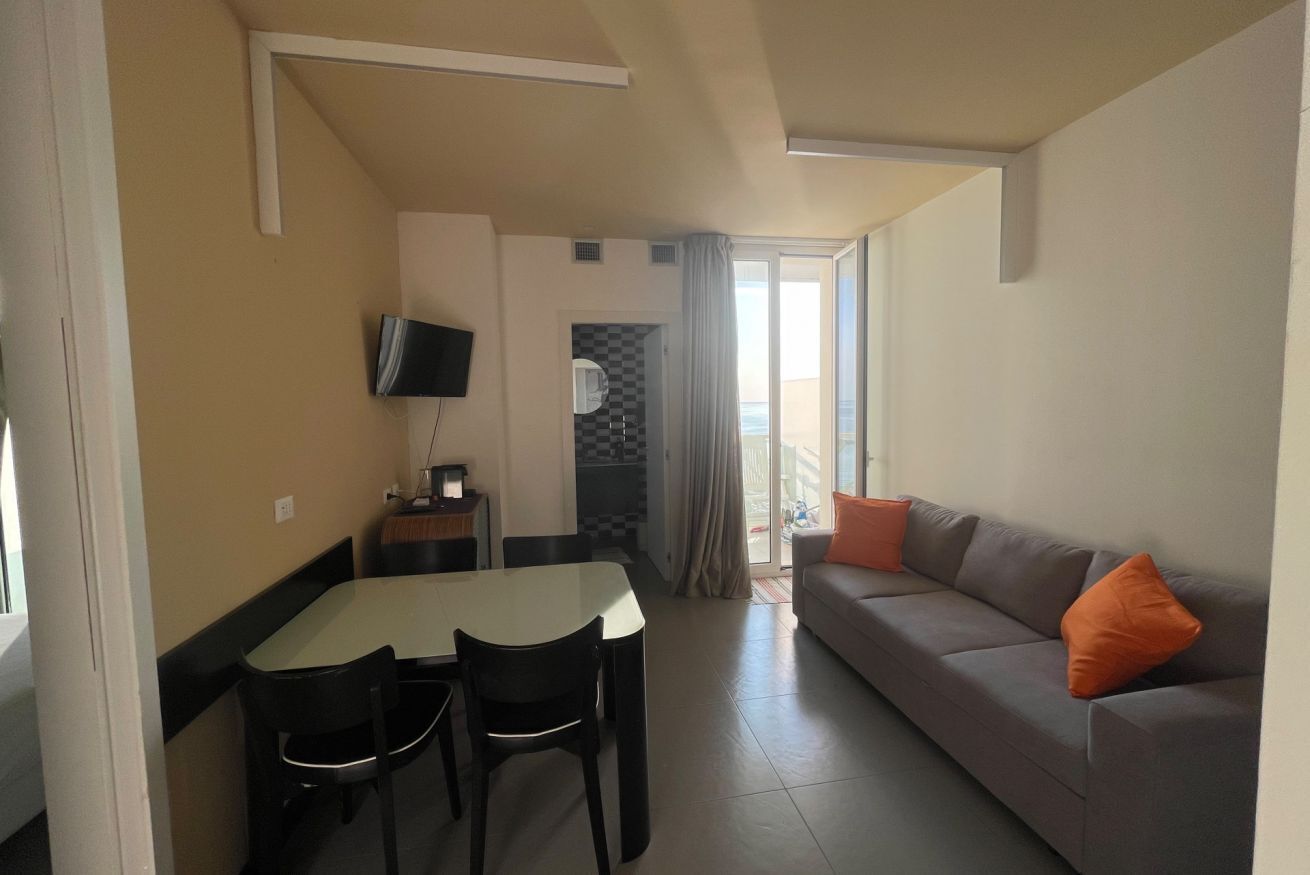 A living room with a sofa and a dining table with chairs.