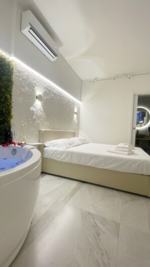 Une chambre à coucher moderne avec une grande baignoire, un lit et un miroir.
