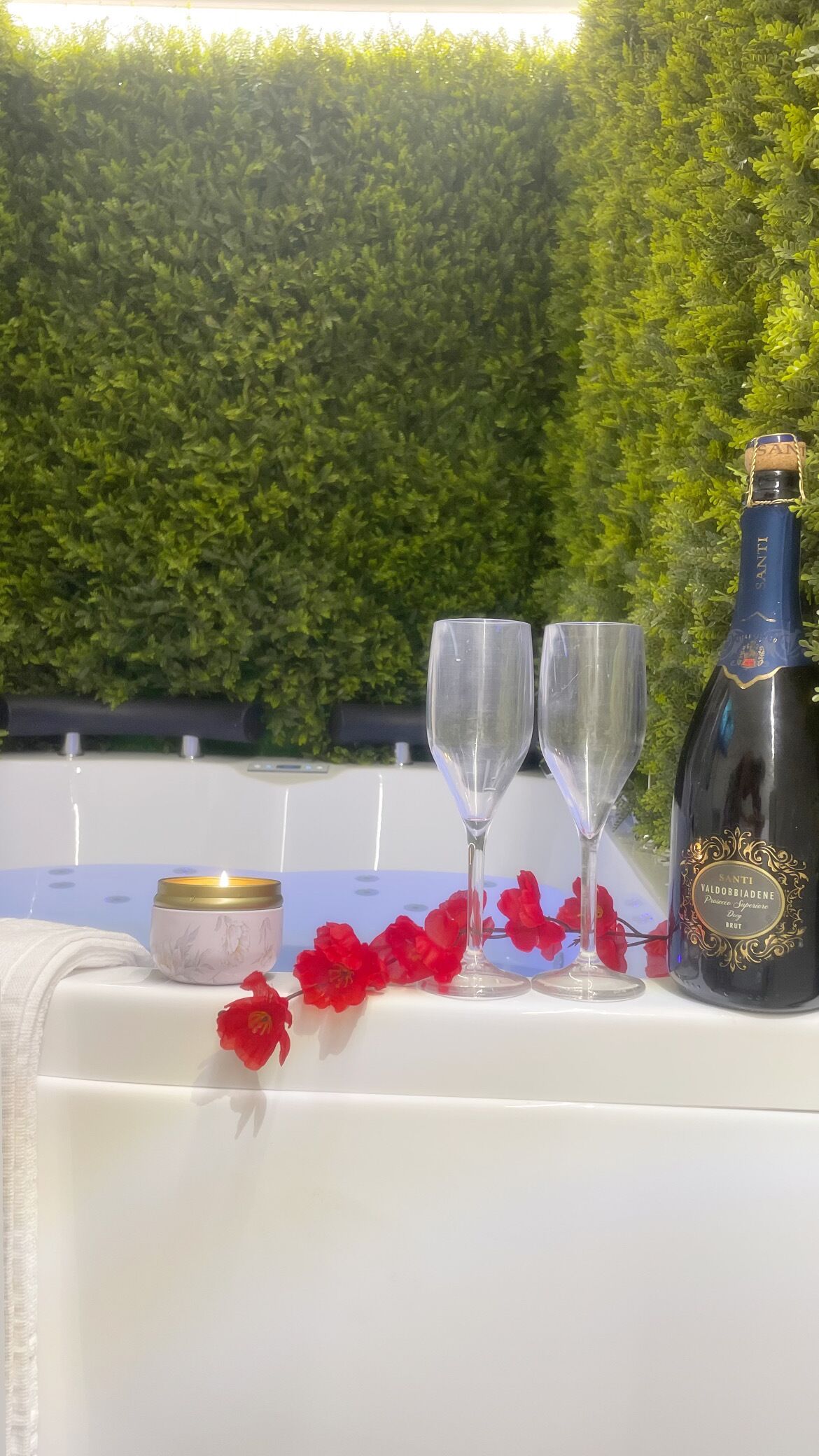 A table set with two wine glasses, a bottle of champagne, and a candle.