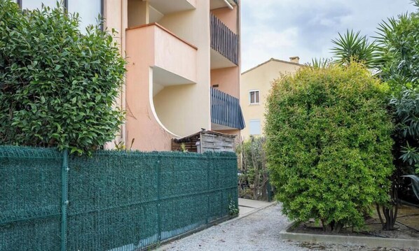 A residential building with a curved balcony, a green fence, and a well-maintained garden. - L'Estiu Bleu - 1BR, Just 450m from the Beach (Argelès-sur-Mer)
