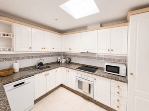A kitchen with white cabinets, a granite countertop, a dishwasher, a microwave, and a toaster. - Cozy 3-bedroom house in Villamartin, Orihuela Costa (Orihuela Costa, Alicante)