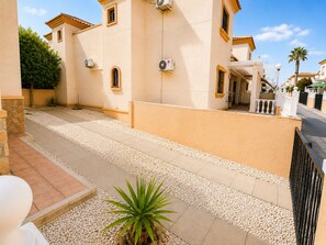 A residential street with beige buildings, a paved walkway, and a palm tree. - Cozy 3-bedroom house in Villamartin, Orihuela Costa (Orihuela Costa, Alicante)