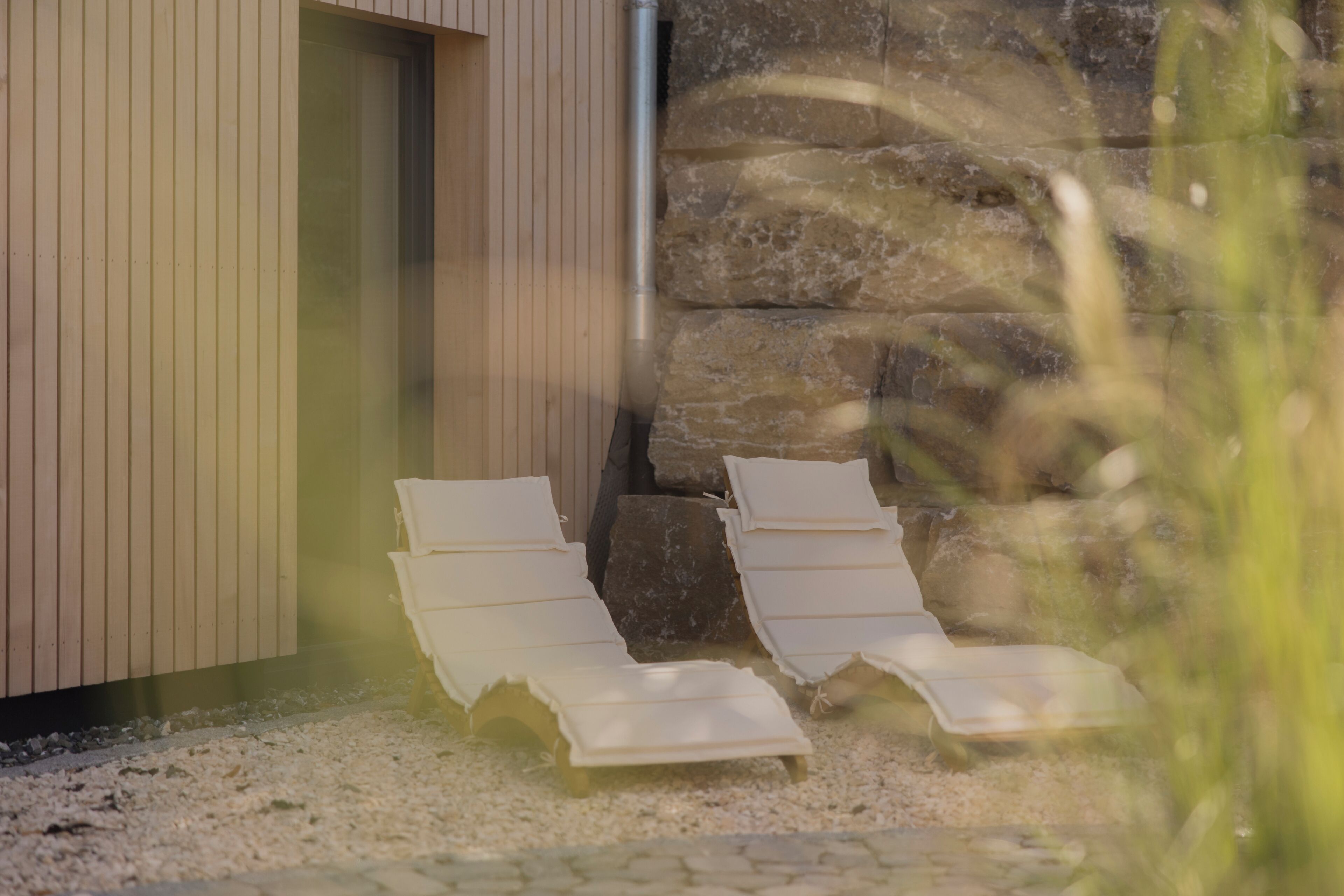 A spa area with two lounge chairs and a stone wall.