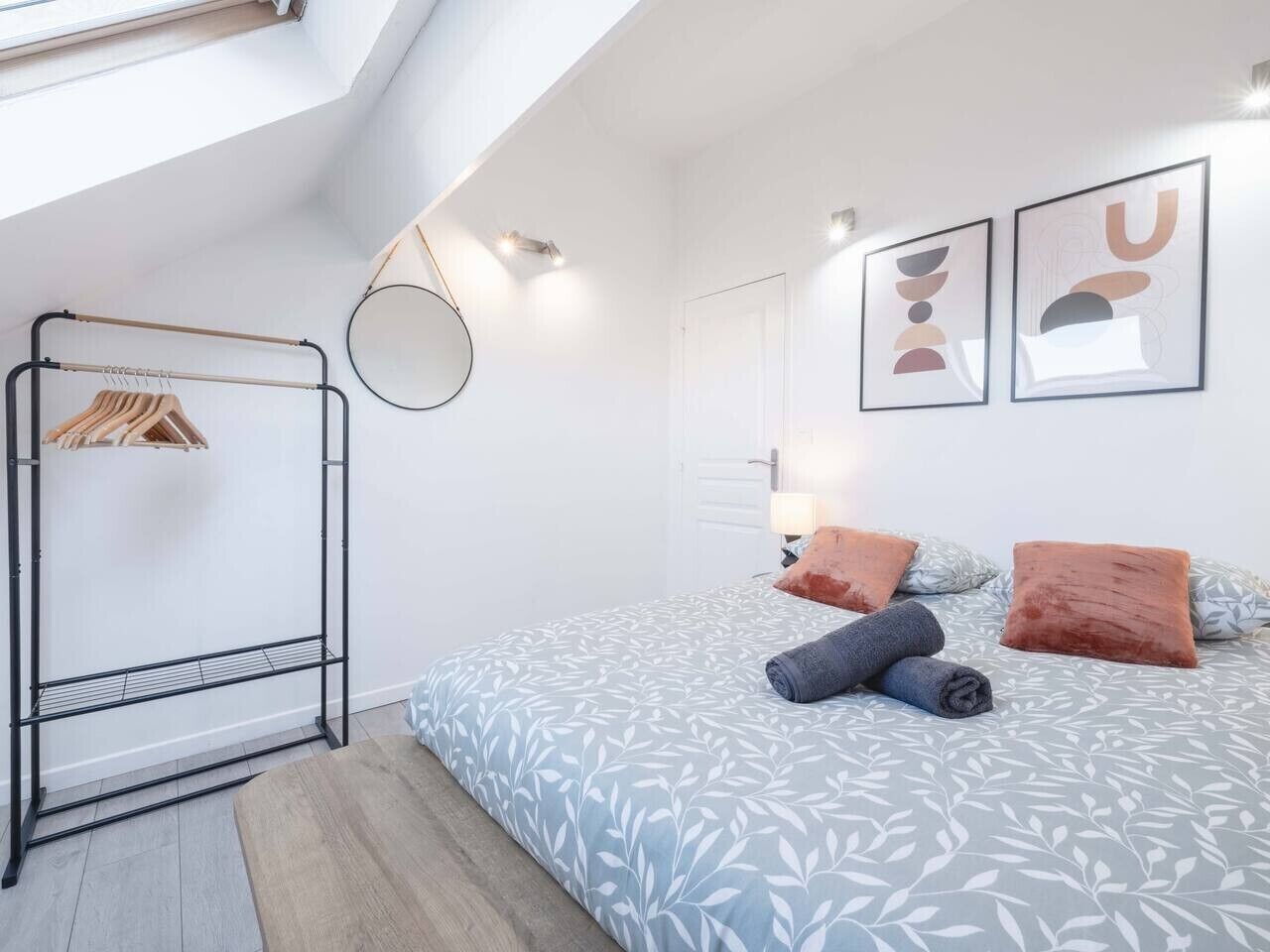 Un dormitorio con una cama, un perchero y una ventana.
