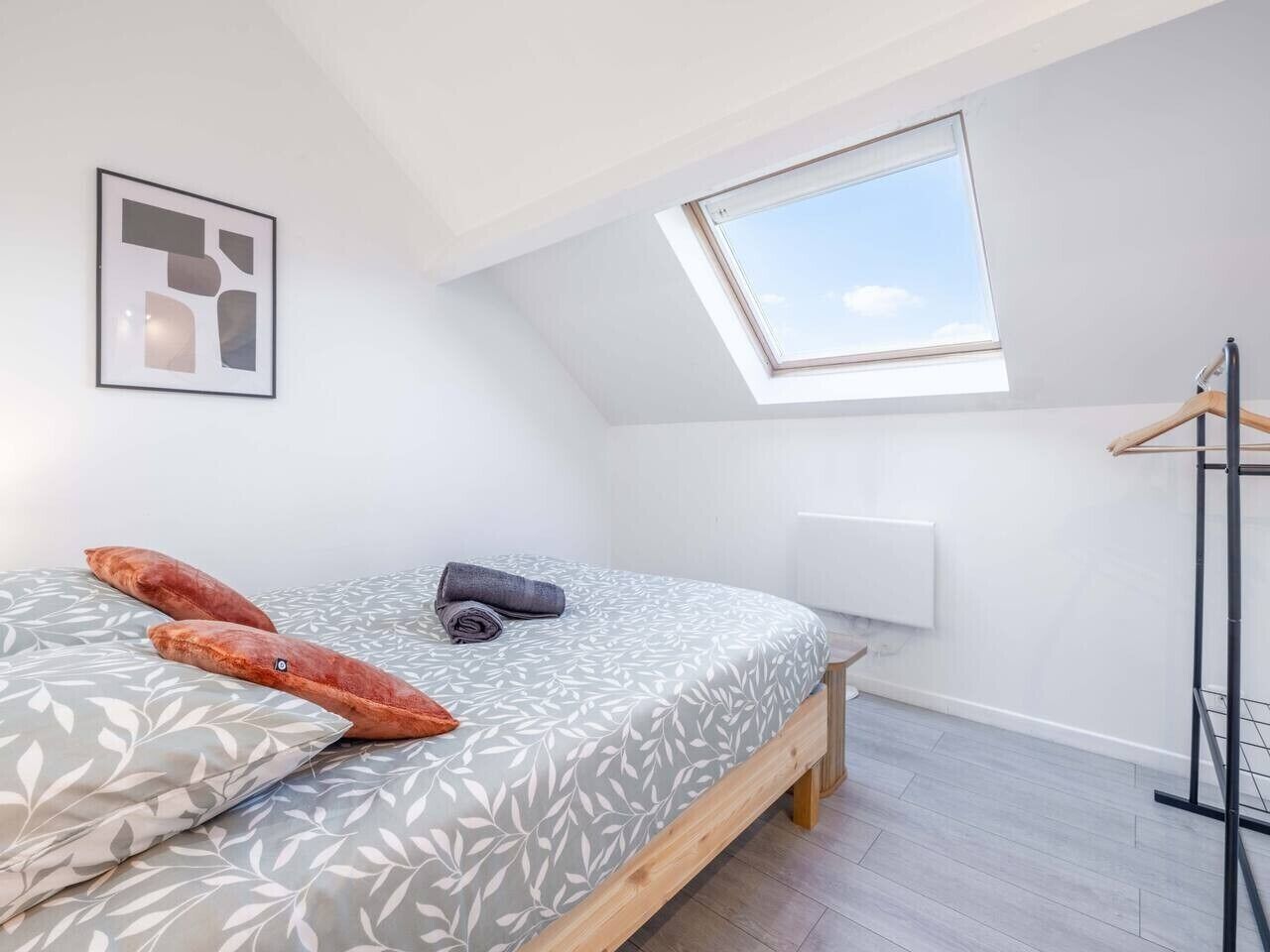 Une chambre avec un puits de lumière, un lit avec une literie à motifs et un radiateur.