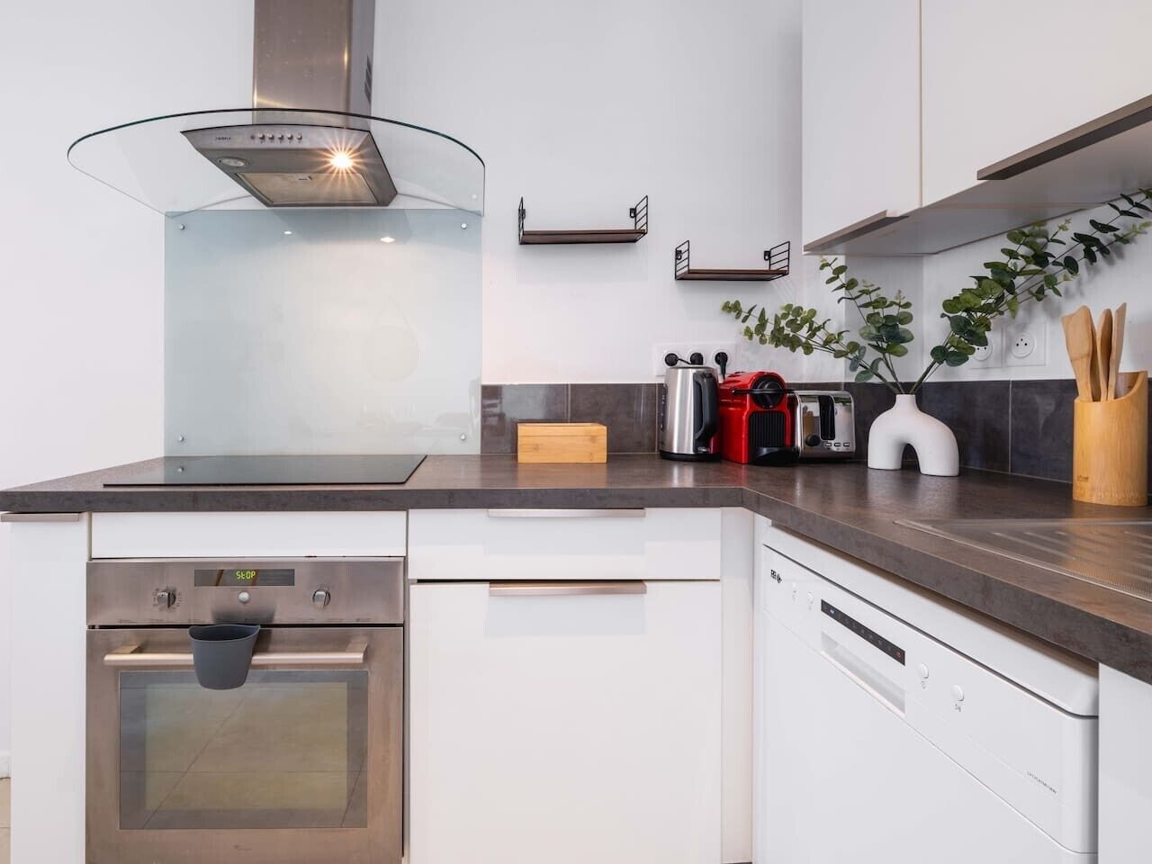 Une cuisine moderne dotée d’appareils électroménagers en acier inoxydable, d’une plaque de cuisson en verre et d’un four encastré.