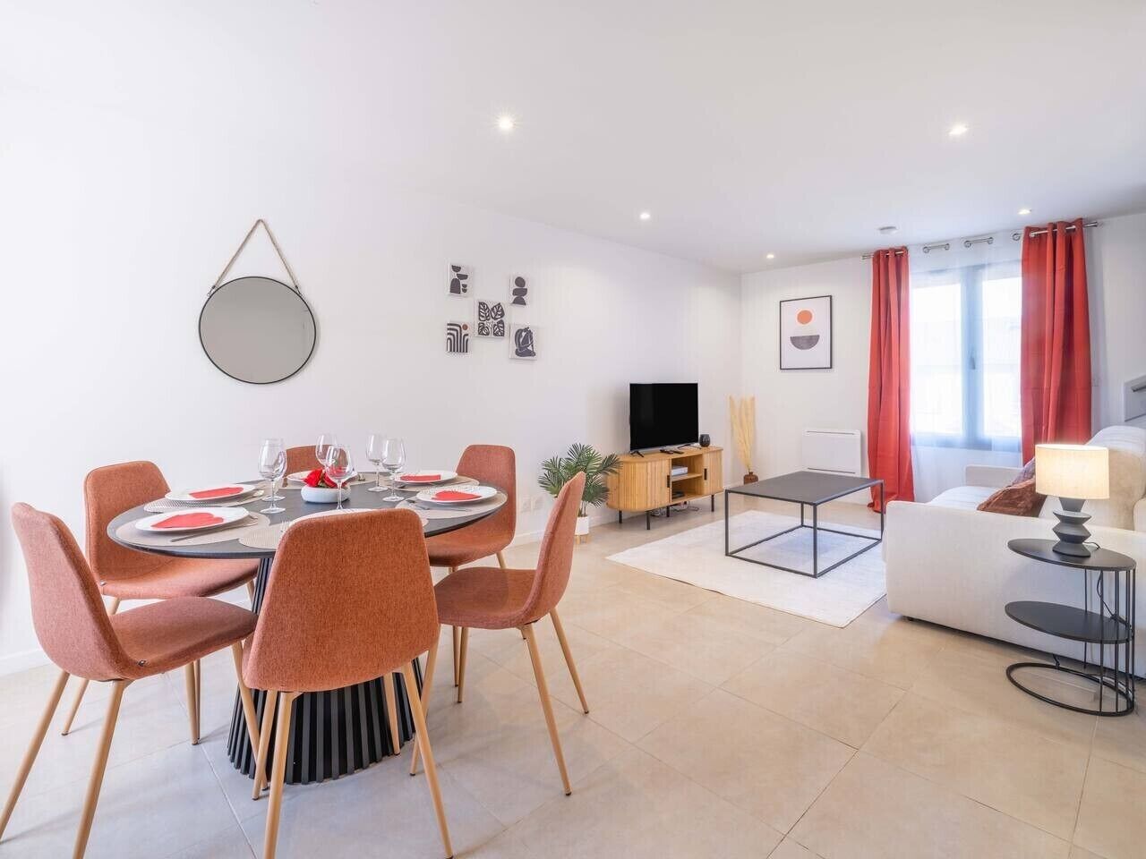 A modern living room with a dining area, a flat-screen TV, and a sofa.