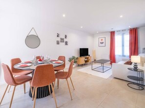 Un salon moderne comprenant un coin repas, un téléviseur à écran plat et un canapé.