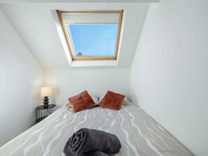 Une chambre à coucher avec un lit, une fenêtre, une table de chevet et une lampe.