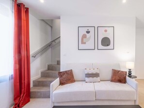 Ein Wohnzimmer mit einer Couch, zwei Kissen, einer Lampe und einer Treppe.