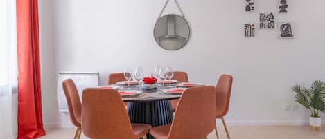 Un comedor con una mesa redonda, seis sillas y una lámpara colgante.