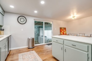 A modern kitchen with a built-in dishwasher, a stainless steel trash can, and a large window. - Retreat on Lake Worth (Fort Worth)