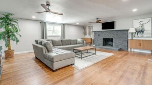 Ein modernes Wohnzimmer mit Ecksofa, Kamin und Deckenventilator.