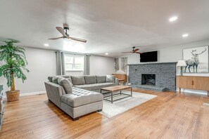 Ein modernes Wohnzimmer mit Ecksofa, Kamin und Deckenventilator.