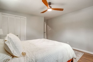 A bedroom with a bed, a ceiling fan, a door, and a white wall. - Retreat on Lake Worth (Fort Worth)