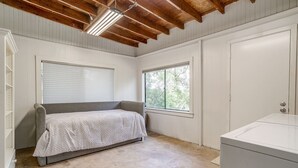 Ein Schlafzimmer mit einem Einzelbett, einem Fenster, einer Heizung und einer Waschmaschine.