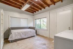 Ein Schlafzimmer mit einem Einzelbett, einem Fenster, einer Heizung und einer Waschmaschine.