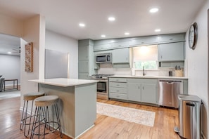 A modern kitchen with grey cabinets, a stainless steel dishwasher, and a built-in microwave. - Retreat on Lake Worth (Fort Worth)