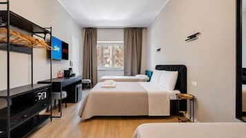 A hotel room with two beds, a desk, a TV, and a window with curtains.